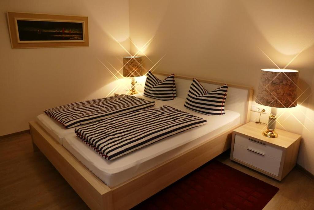 ein Bett mit schwarzen und weißen Kissen und zwei Lampen in der Unterkunft Baltic Nr. 27 in Scharbeutz