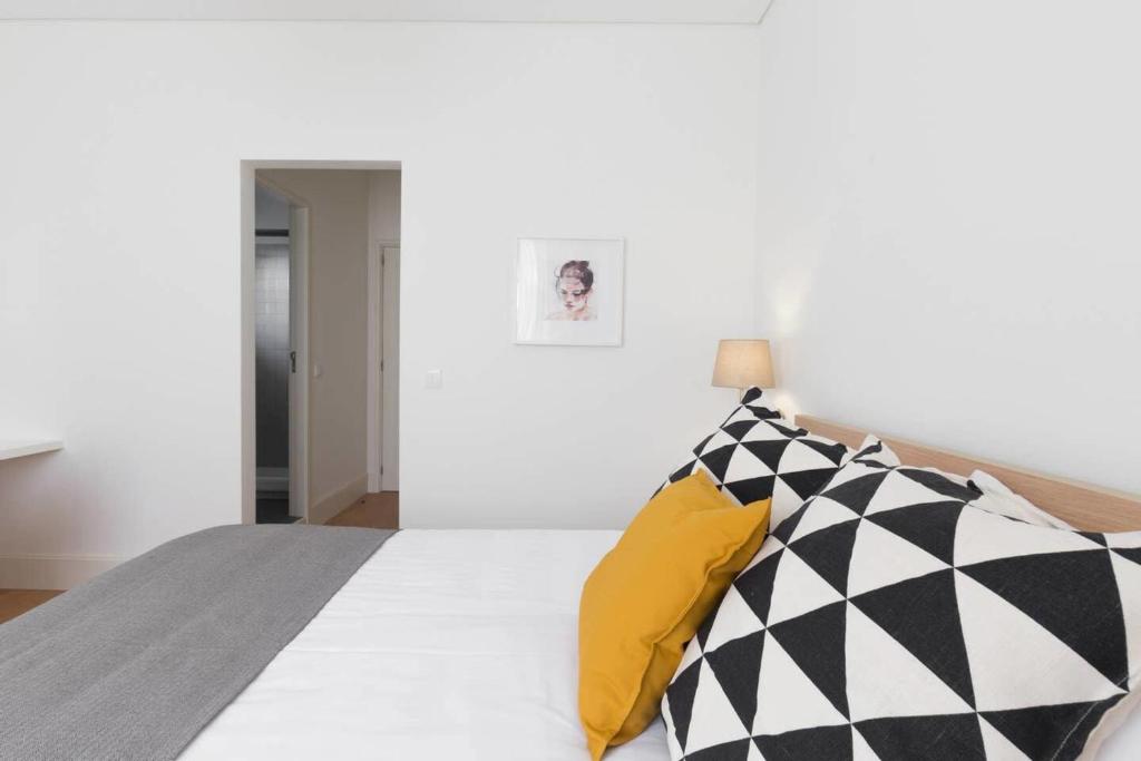 ein Schlafzimmer mit einem Bett mit schwarzen und weißen Kissen in der Unterkunft GuestReady - Costa Cabral Guesthouse in Porto