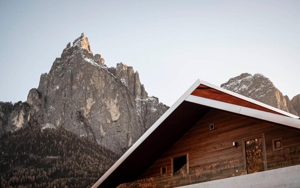 un bâtiment avec une montagne en arrière-plan dans l'établissement La Paula Apartments & Suites, à Alpe di Siusi