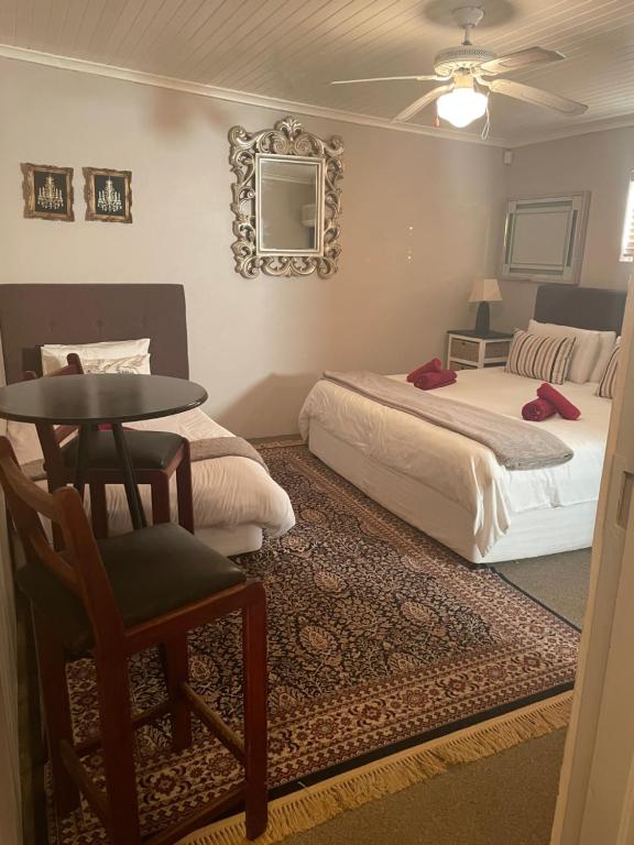 a bedroom with two beds and a table and a chair at 90 On Wellington Cottage in Port Elizabeth