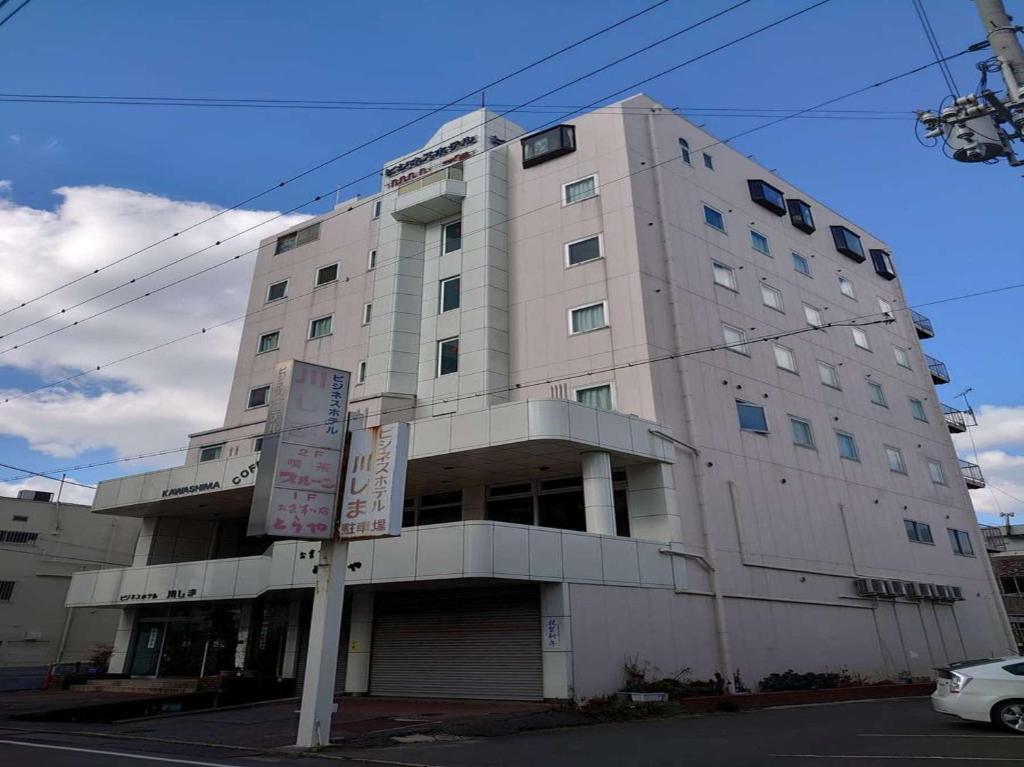 a large white building on the corner of a street at Business Hotel Kawashima in Wakayama