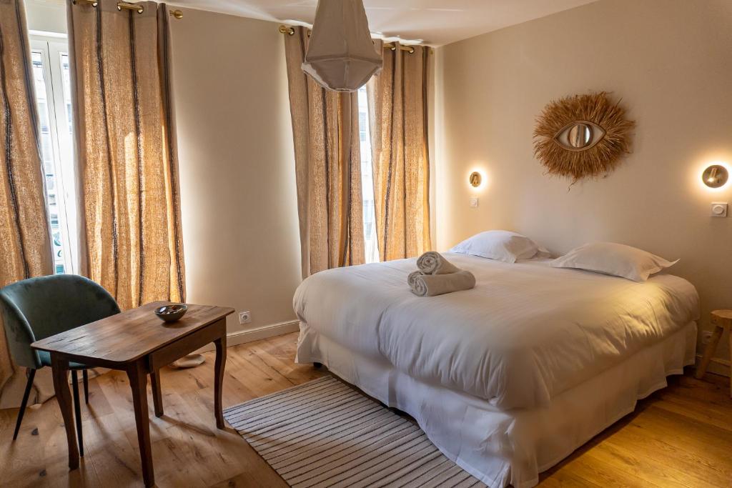 ein Schlafzimmer mit einem großen weißen Bett und einem Tisch in der Unterkunft Les Nids Perchés - Rue Sainte Croix in Mortagne-au-Perche