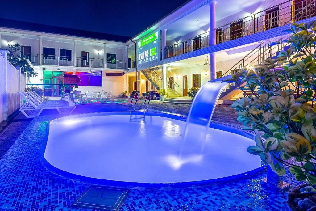 a swimming pool with a fountain in the middle of a building at Mini Hotel Platan in Tsandrypsh