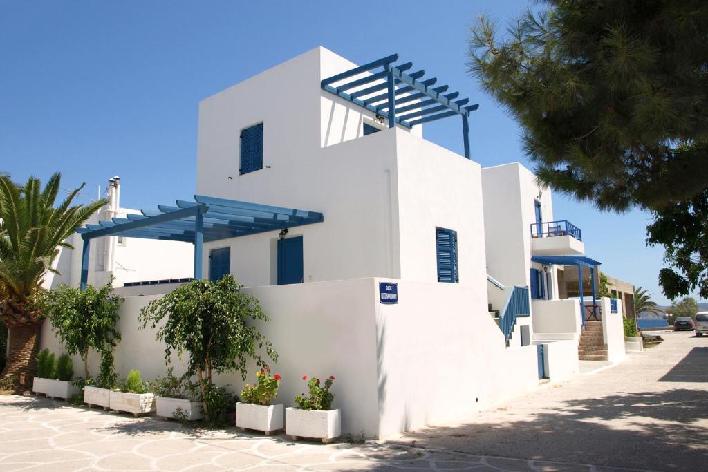 a white building with blue roofs on a street at Artemis Bakerys House 2 in Adamas