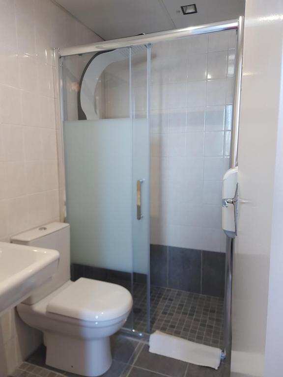 a bathroom with a toilet and a glass shower at Hotel de Normandie in Saint-Aubin-sur-Mer