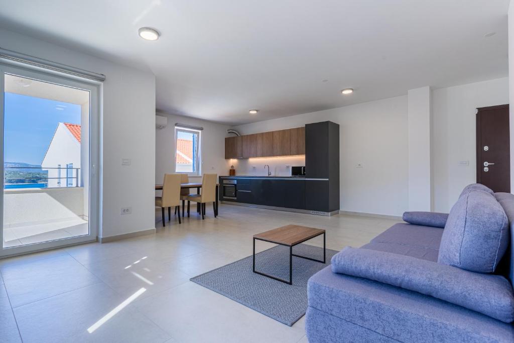a living room with a blue couch and a kitchen at Sunset Apartment in Cres