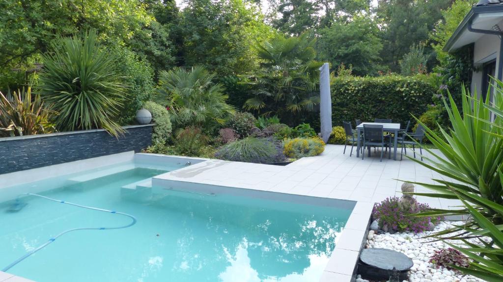 uma piscina no meio de um jardim em Villa d’archi. piscine privée en écrin de verdure em Mérignac