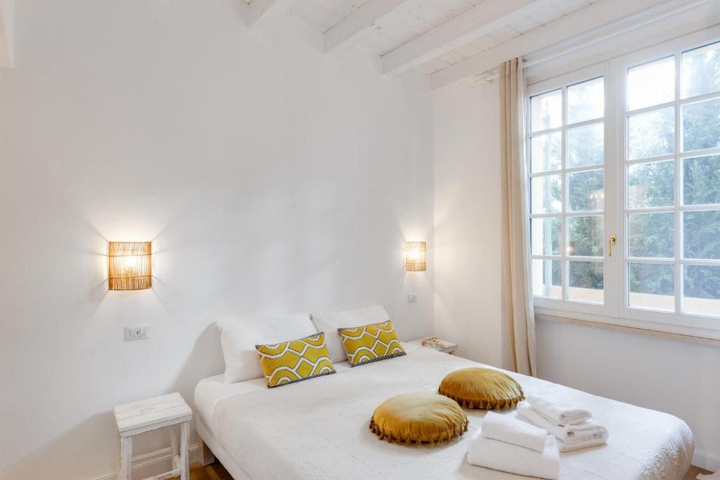 a white bedroom with a bed and a window at Maison d'Orange - La Pinede in Saint-Tropez