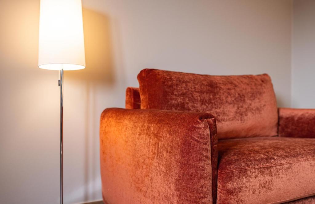 a brown chair sitting next to a floor lamp at Hotel Monvillage in Mondercange