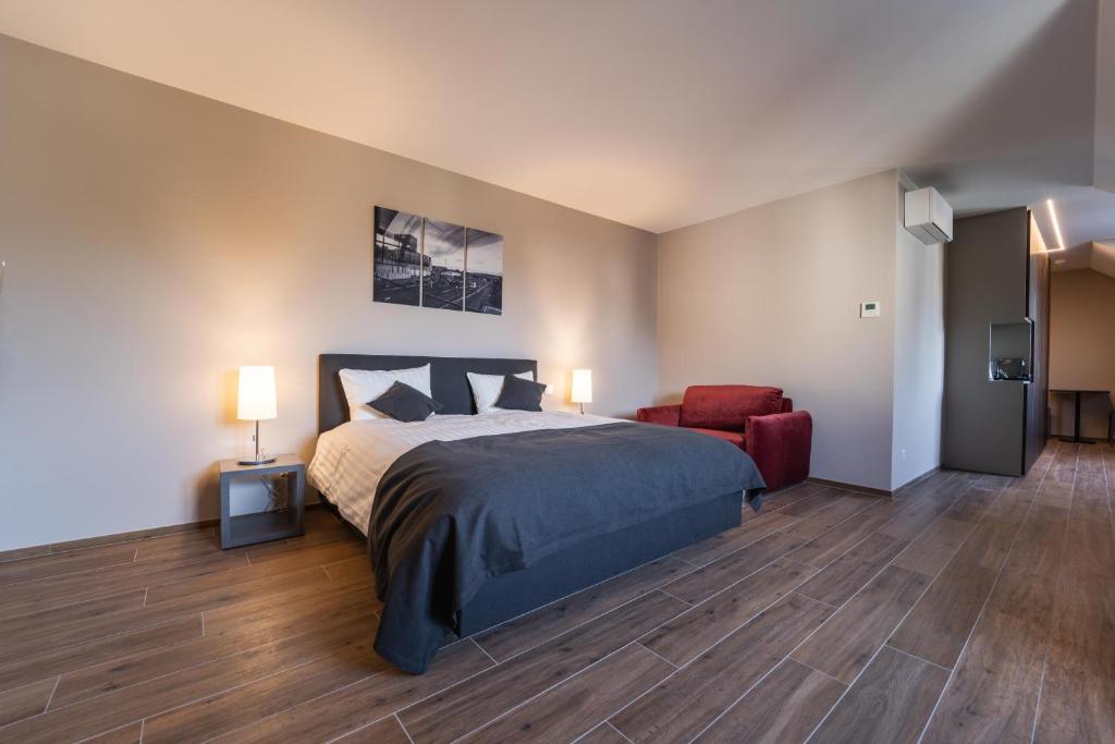 a bedroom with a bed and a red chair at Hotel Monvillage in Mondercange