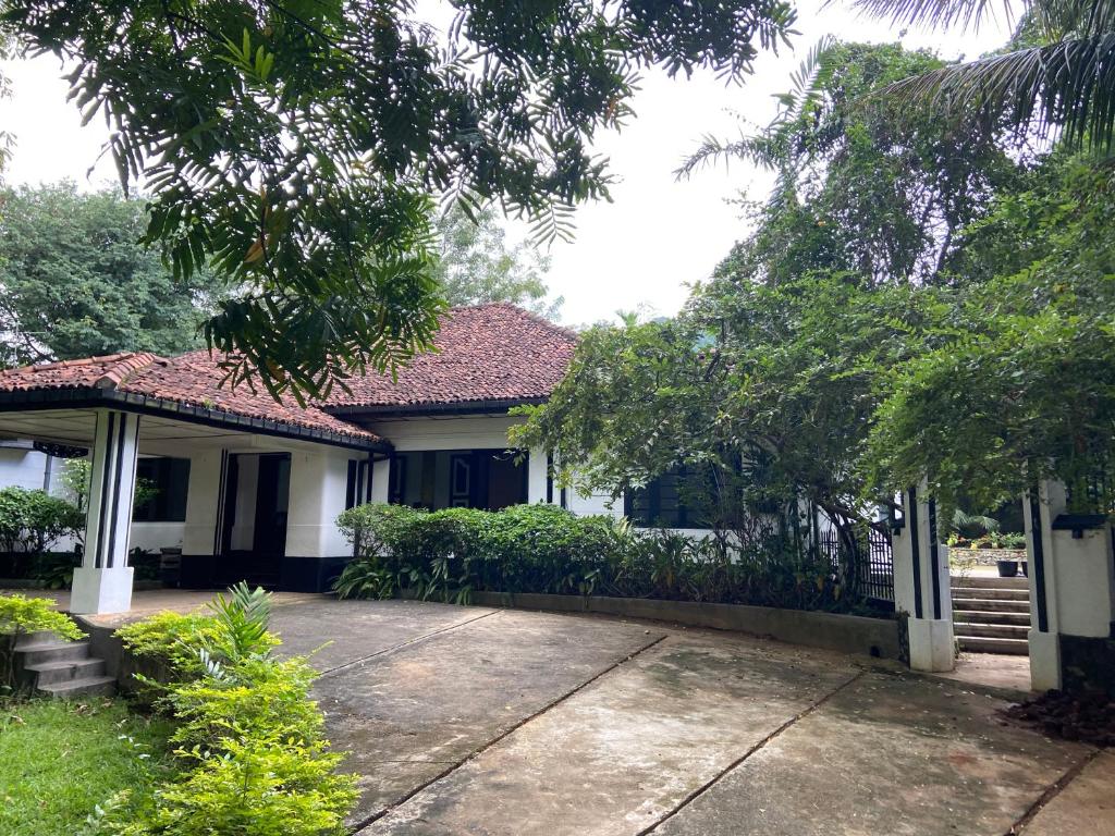 ein Haus mit einem Zaun und einer Einfahrt in der Unterkunft Clover Grange Home Stay in Matale