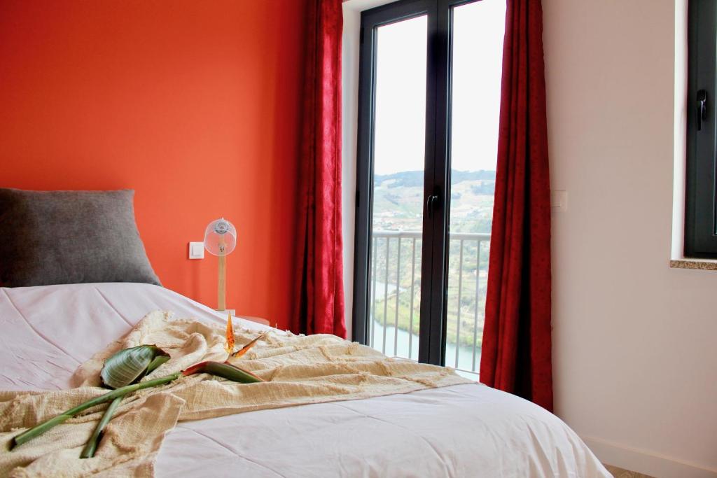 1 dormitorio con paredes de color naranja y 1 cama con ventana en Quinta do Fojo Valonguinho, Barrô, en Barrô