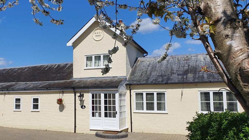 una casa blanca con techo negro en Exclusive Coach House with Lakeside Hot Tub on Country Estate en Toddington