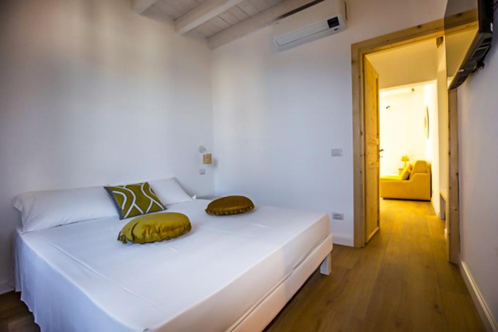 a bedroom with a white bed with yellow pillows on it at Maison d'Orange - La Pinede in Saint-Tropez