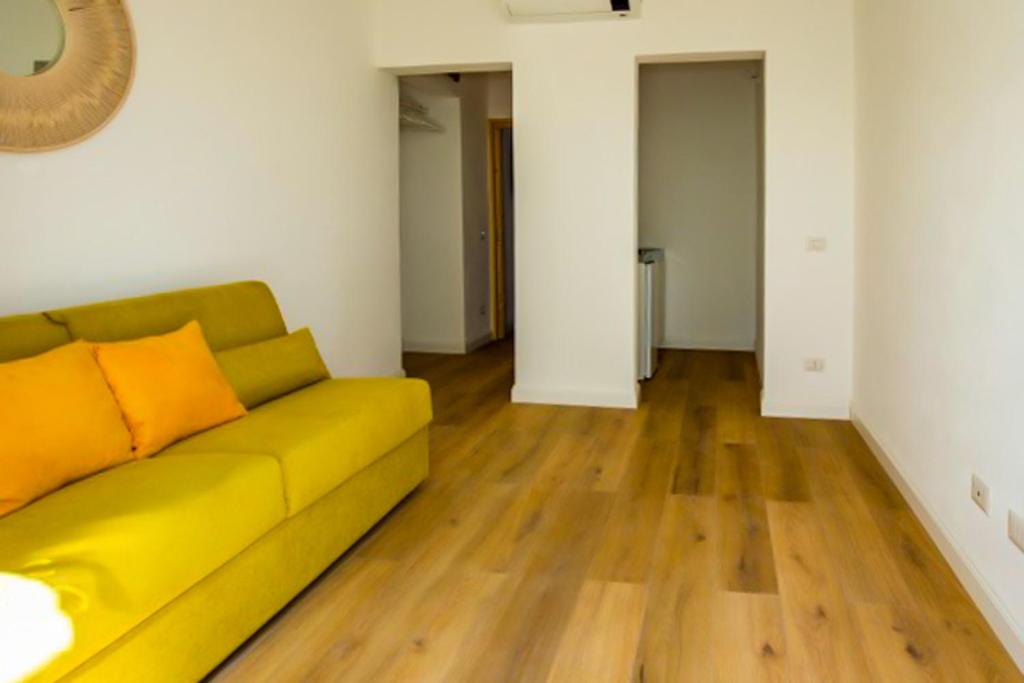 a living room with a yellow couch and wooden floors at Maison d'Orange - La Pinede in Saint-Tropez
