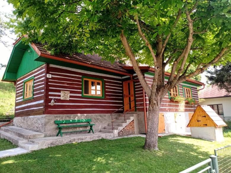 una pequeña casa con un banco verde delante de ella en Drevenica RAKŠA 11 en Rakša