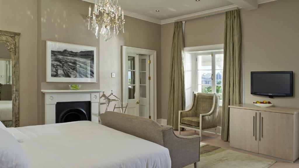 开普敦Dock House Boutique Hotel and Spa by NEWMARK的一间卧室配有一张床、一台电视和一个壁炉