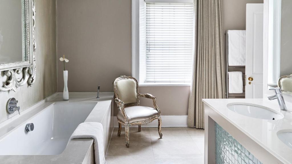 开普敦Dock House Boutique Hotel and Spa by NEWMARK的浴室设有椅子,位于浴缸旁
