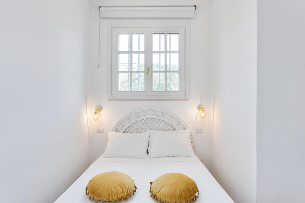 a white bedroom with a bed with two gold pillows on it at Maison d'Orange - La Pinede in Saint-Tropez