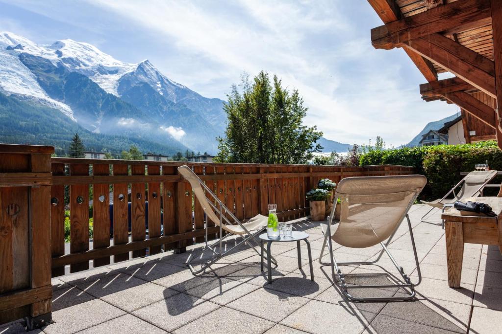 twee stoelen en een tafel op een balkon met bergen bij Chalet La Chaumière in Chamonix-Mont-Blanc