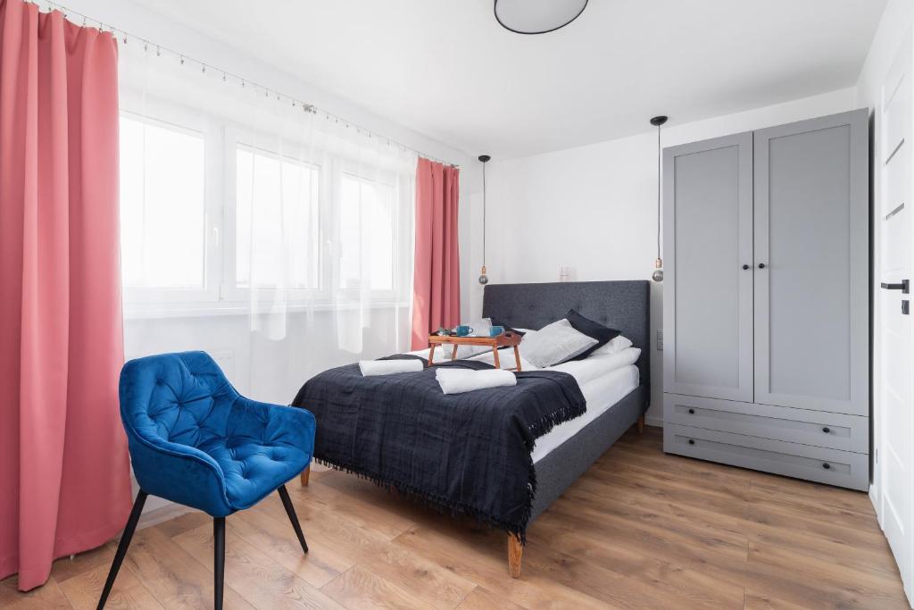 Apartments Kraków Czarnowiejska by Renters في كراكوف: غرفة نوم بسرير وكرسي ازرق