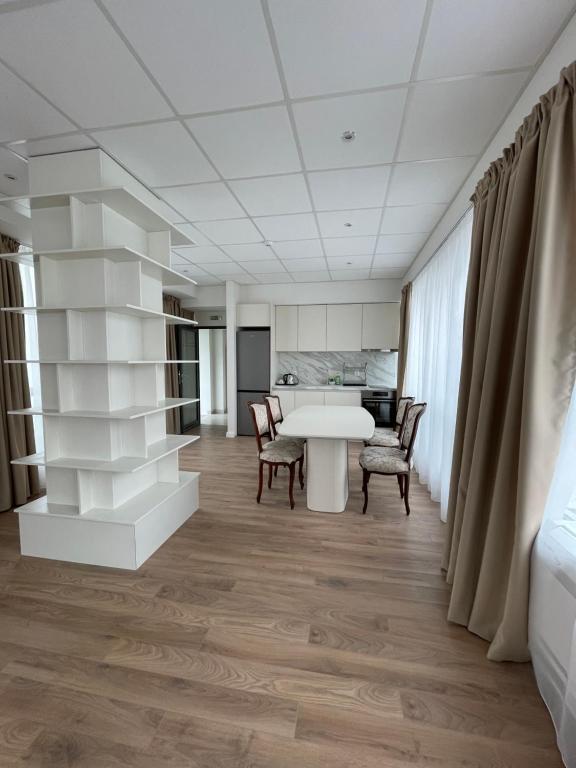Habitación con mesa blanca, sillas y cocina. en FELIX KANITZ Apartments - in the heart of Kapana district, en Plovdiv