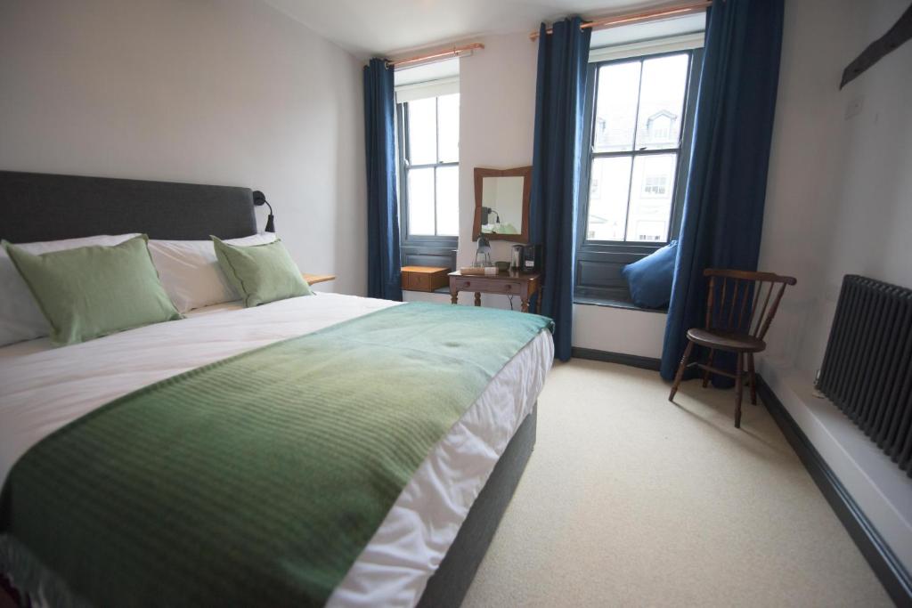 Un dormitorio con una cama grande y dos ventanas. en Royal Oak Pub, en Cartmel