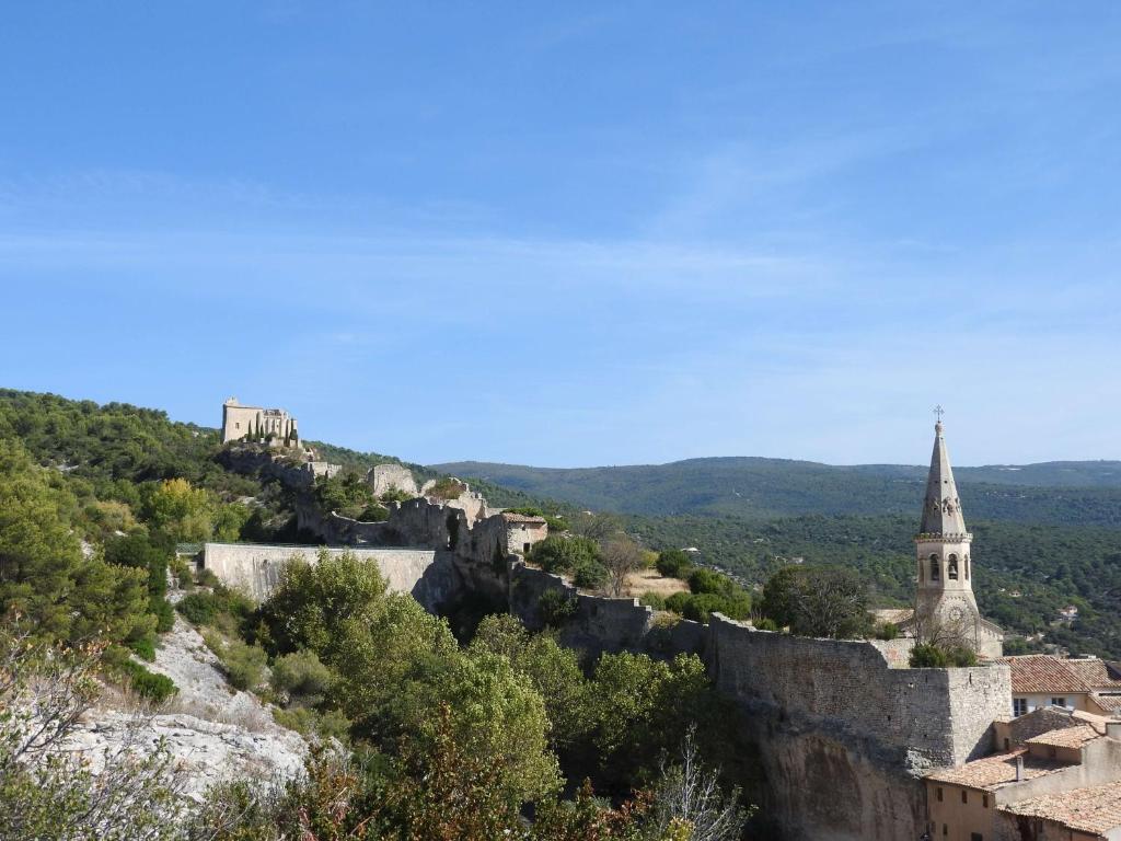 una vista de un castillo y una iglesia en una colina en Luberon maison au cœur d'un village provençal en Saint-Saturnin-dʼApt