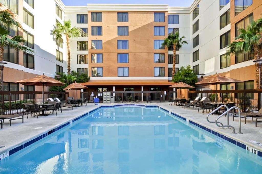 an outdoor swimming pool with tables and chairs and a building at Hyatt Place Las Vegas in Las Vegas