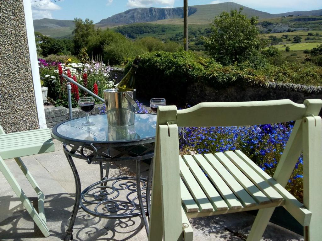 a glass table and a bench on a patio with flowers at Hyfrydle Heights in Pen-y-groes