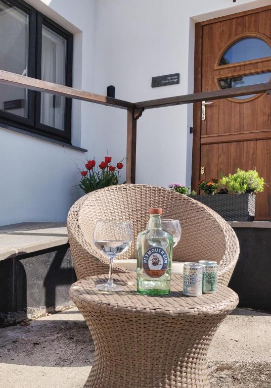 a bottle of alcohol and a glass on a wicker chair at Darracott Farm Cottage in Welcombe