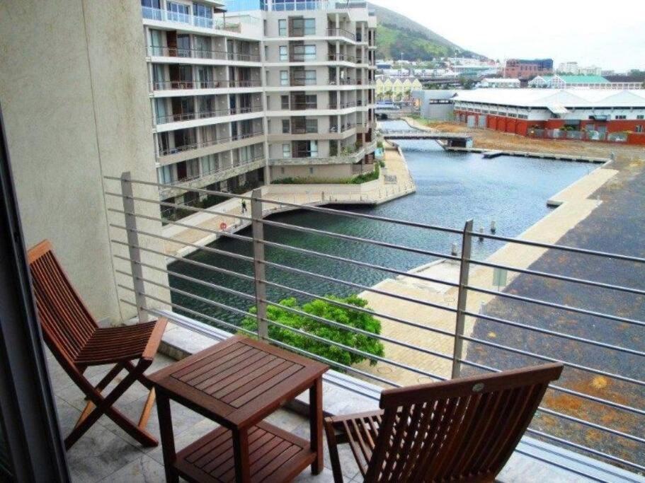 a balcony with two chairs and a table and a river at 312 HARBOUR BRIDGE in Cape Town