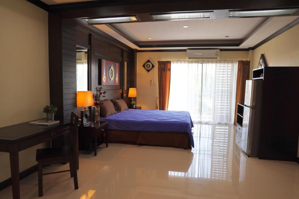a bedroom with a bed and a table and a desk at THOMLEK Guesthouse in Cha Am