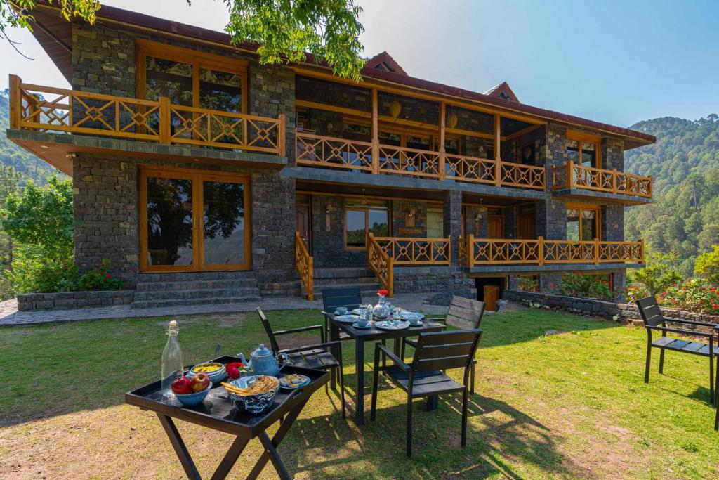 a house with a table and chairs in front of it at StayVista at Mountain Mirage 4BR Luxury Villa in Kasauli with Spa, Lawn, Hillview in Solan