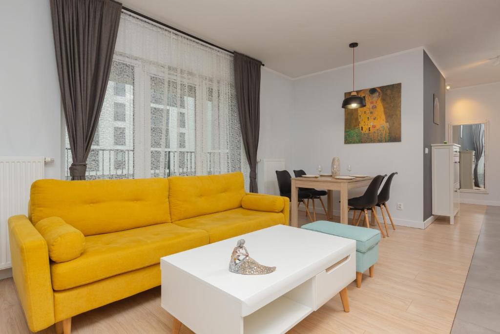 sala de estar con sofá amarillo y mesa en Active City Apartments Warsaw by Renters, en Varsovia