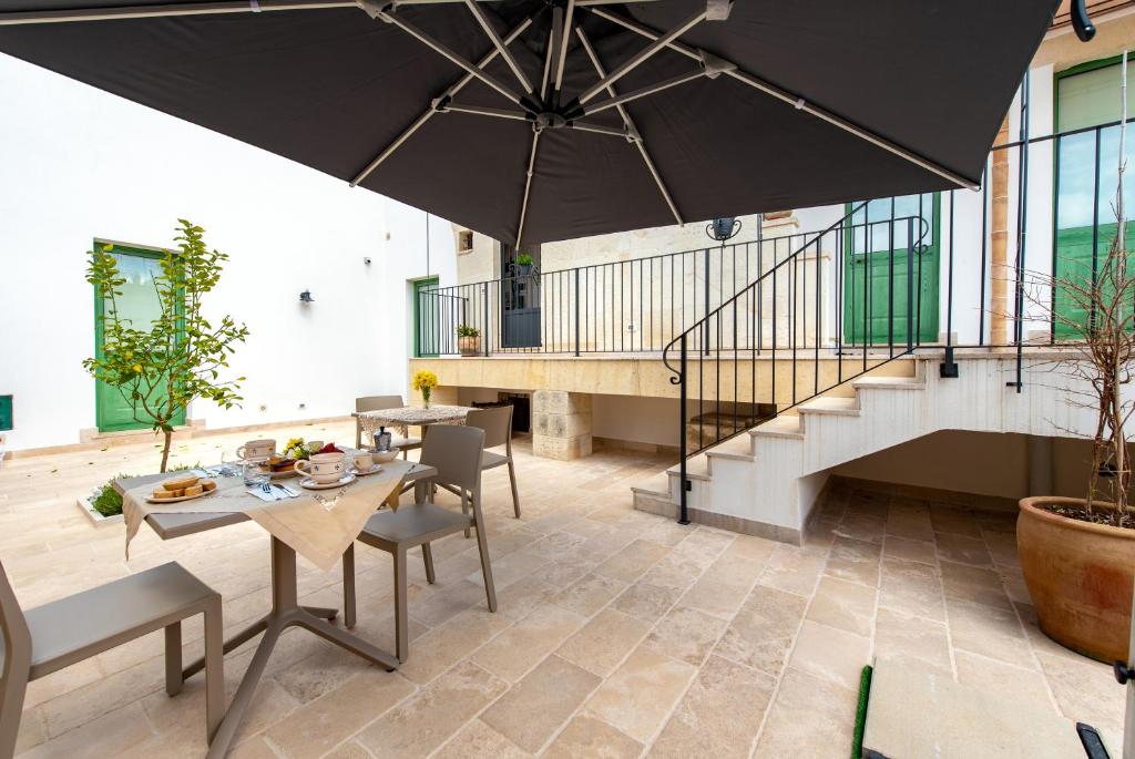 eine Terrasse mit einem Tisch und einem großen Sonnenschirm in der Unterkunft MIOE in Muro Leccese