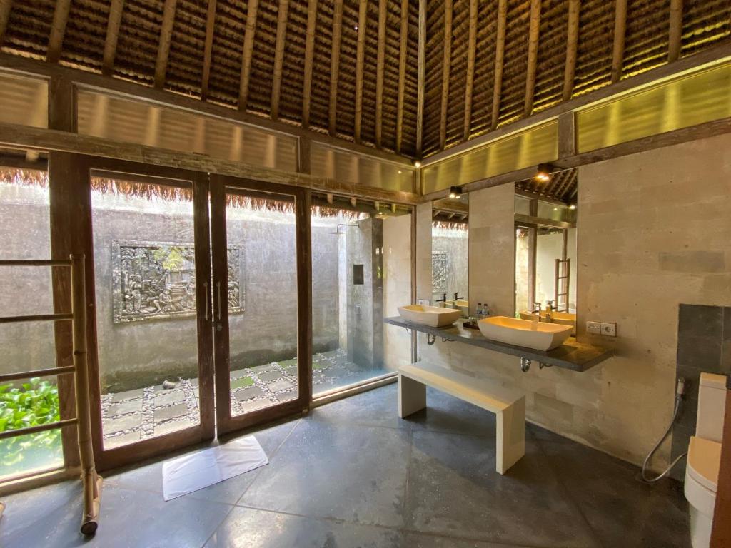 a bathroom with two sinks and a large window at Sawah Indah Villa in Sidemen