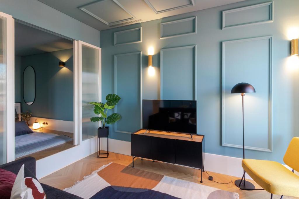 sala de estar con paredes azules, TV y sofá en HM - Infante Riverside Apartment K en Oporto