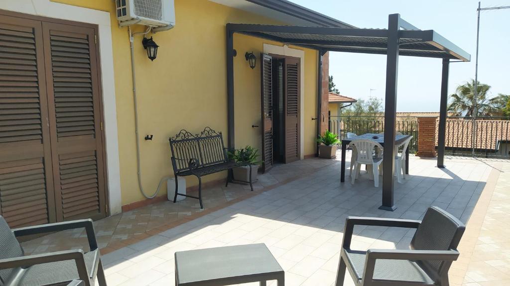 eine Terrasse mit Stühlen, einem Tisch und einem Sonnenschirm in der Unterkunft La Terra Patrizia in Nicolosi