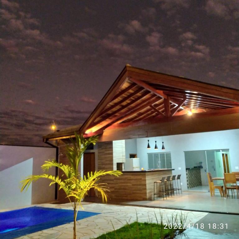 a house with a kitchen and a swimming pool at night at Recanto Asa Delta in Olímpia