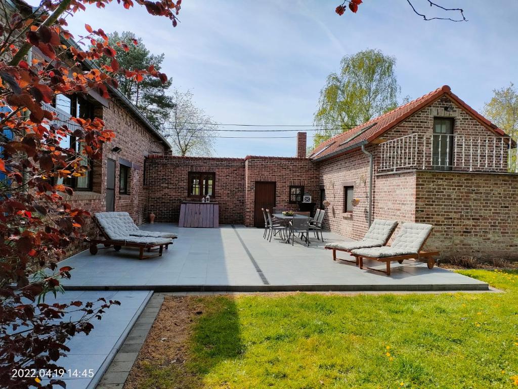 a patio with two chairs and a table in front of a brick building at De Stille Weier in Genk