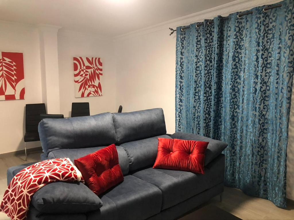 a couch with two red pillows on it in a living room at casa Encarni, balcon de las cuevas in Setenil