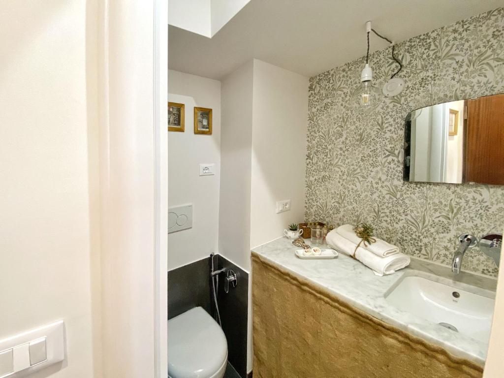 łazienka z umywalką, toaletą i lustrem w obiekcie Casa Ginepro via Mazzini w Turynie