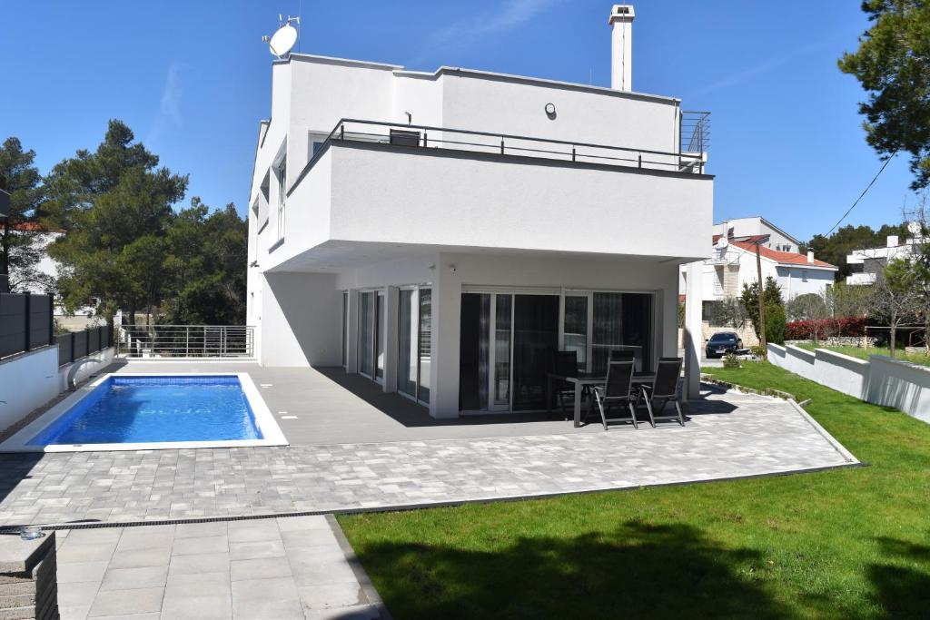 a white house with a swimming pool and a yard at Villa Dalija in Biograd na Moru