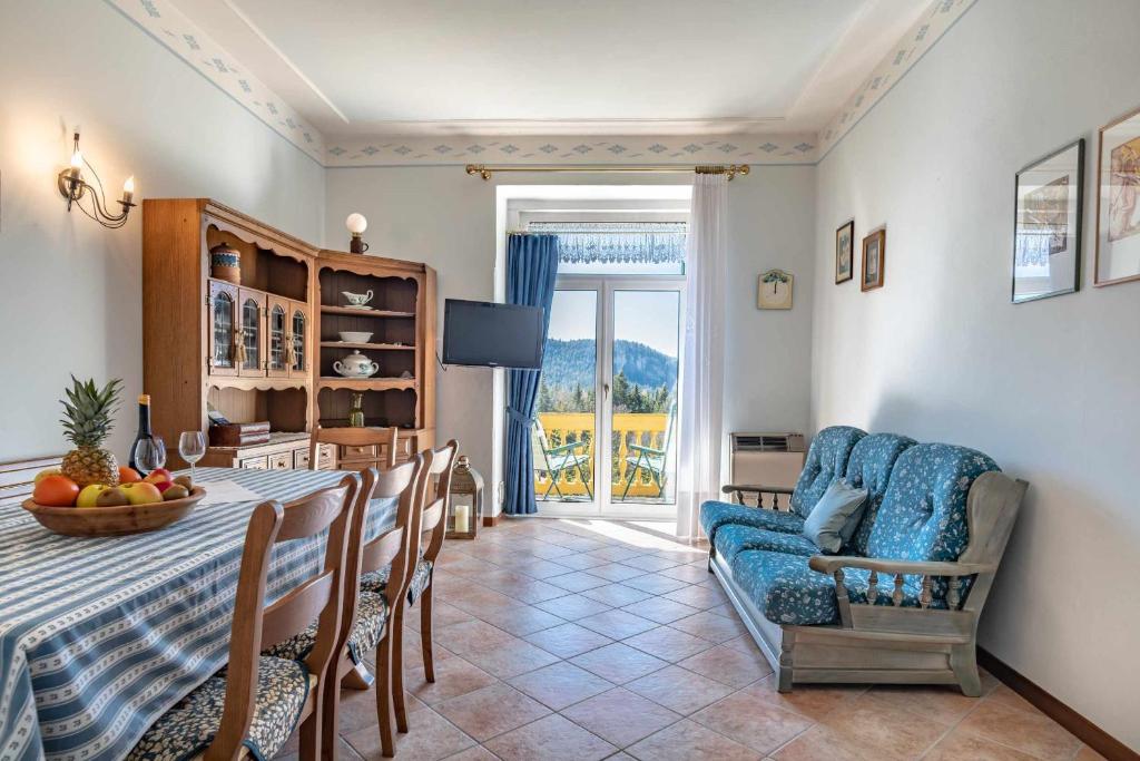 a dining room with a table and a blue couch at Dimora imperiale Passo Mendola OSPITAR in Trento