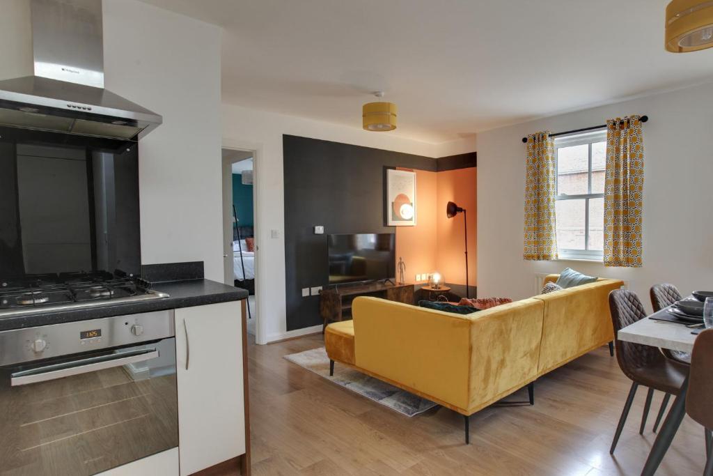 een keuken en een woonkamer met een gele bank bij Cosy Two Bedroom Coach House - Free Parking for 2 vehicles, WIFI & Netflix in Colchester