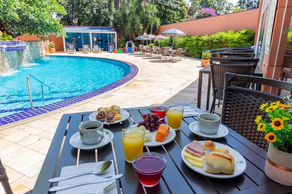 a table with food and drinks next to a swimming pool at Hotel Golden Park Ribeirão Preto in Ribeirão Preto