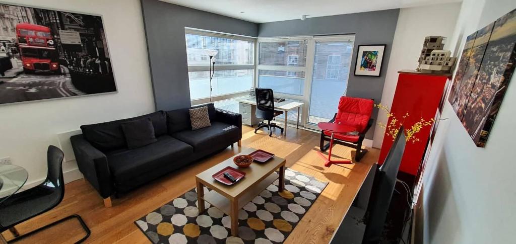 sala de estar con sofá negro y silla roja en Bright & spacious Double Bedroom with EnSuite and Concierge! Paid parking available, en Londres