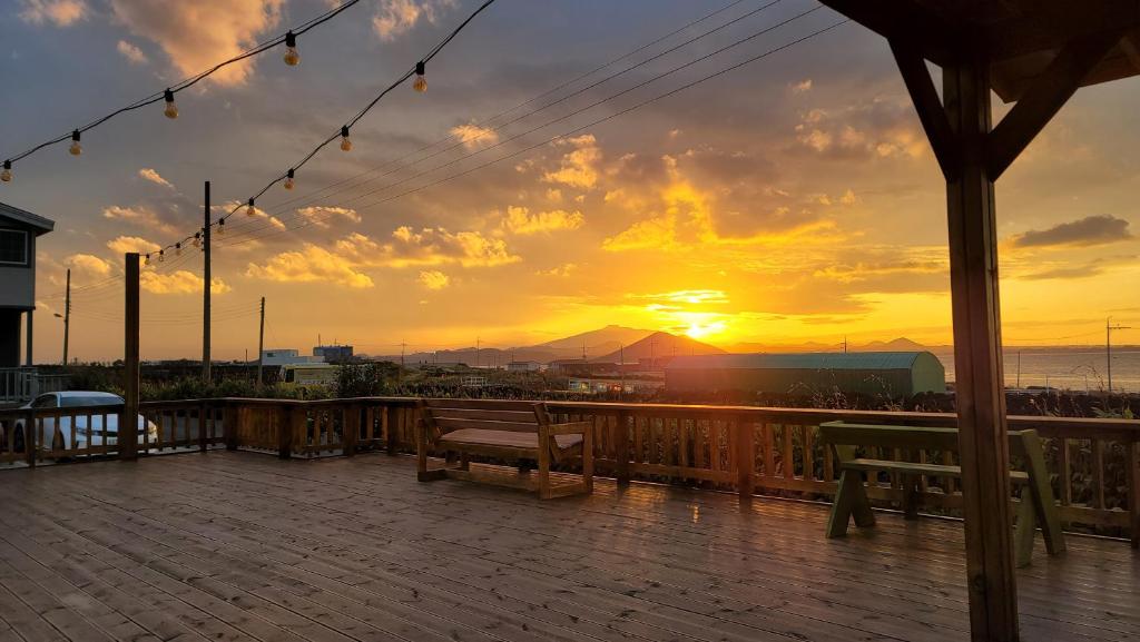 a deck with a bench and a sunset in the background at Haumok52 Udo in Jeju