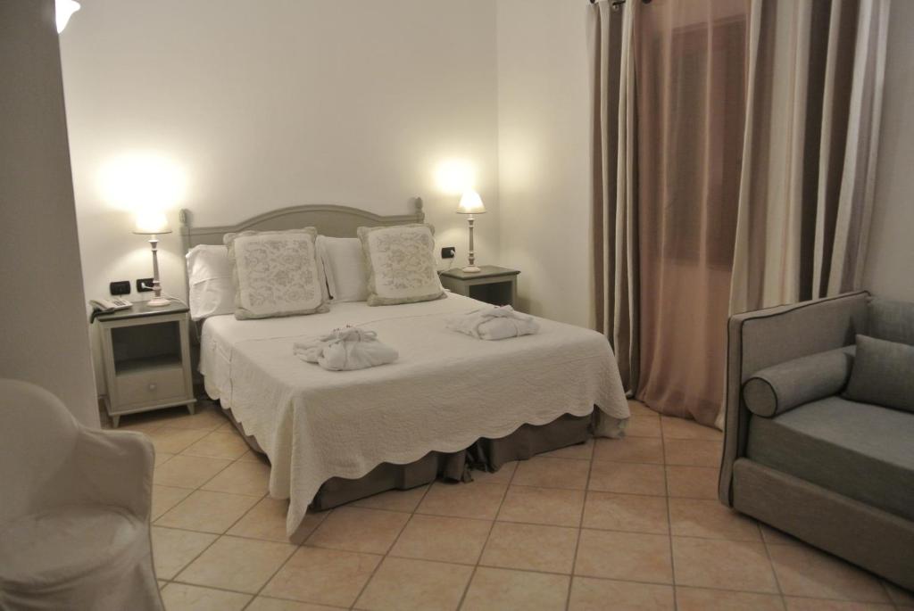a bedroom with a bed and a couch and a chair at Relais Fenicottero Rosa in Porto San Paolo